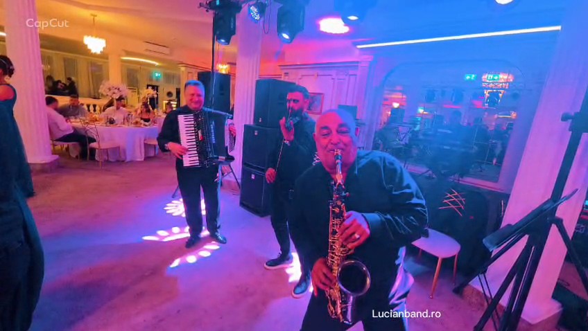 Saxofonistul Lucian Band cântă aproape de invitați, alături de acordeonist și solist.